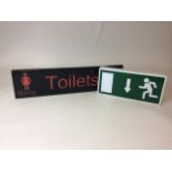 Two electrified signs. A single sided Girls/Boys toilet sign and a single sided fire exit sign.