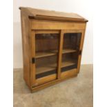 A light oak library bookcase with double sliding glazed doors and brass handles also with hinged