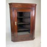 A mahogany and oak corner cupboard with large glazed door, three shelves and central drawer. W: