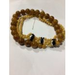 A string of amber beads together with a large strand of faux amber beads.