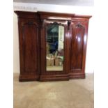 A large Victorian mahogany break front wardrobe, with large central mirror door and