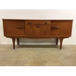 A mid century G Plan style side board with concaved front, cupboards either side of central drawer
