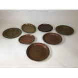 Eight metal display plates, made from copper and brass.