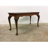 A rectangular coffee table with pie crust edge carved legs and pad feet.