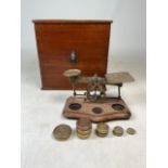 A mahogany box with postage scales together with nine weights: 8oz to 1/2 oz.