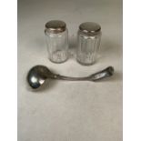 A white metal soup ladle together with a pair of white metal topped dressing table jars.