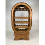 A pine wine rack in the shape of a barrel, houses twenty one bottles with hanging for wine