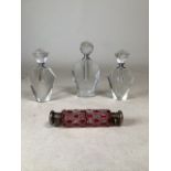 Three Art Deco style cut glass perfume bottles, largest 17cm height with cut glass cranberry