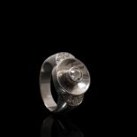 A French platinum and diamond ring. Central 5 mm old cut bezel set diamond within a platinum halo