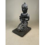 A kneeling Buddha composite statue with white paint detailing and holding a bowl with a felt