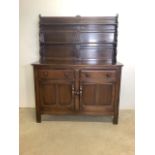 An Ercol mid century stained oak two piece dresser with plate rack top sideboard beneath with two