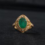 An 18ct gold emerald and diamond ring. Central oval free cut bezel set emerald (11mm x 9mm ) with