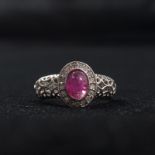 An 18ct white gold ruby and diamond ring. Central cabochon cut Burmese ruby with diamond