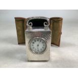 A sterling silver carriage clock. White enamel face with Arabic markers to a hand planished case