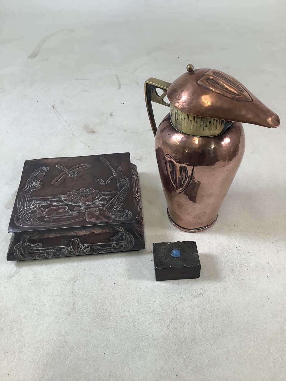 Three Arts and Crafts items to include a lidded copper and brass jug, a copper lidded box and a