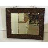 An oak carved wall mirror with bevelled edge. W:87cm x H:42cm
