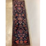 A dark blue ground runner with colourful decoration.W:310cm x D:87cm