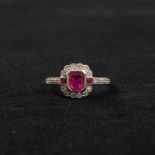 An 18ct white gold ruby and diamond art deco style ring. Central bezel set emerald cut ruby with