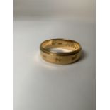 An 18ct gold gents wedding band with chased decoration. 4.3G Size R.