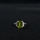 A platinum diamond and peridot art deco style ring. Central step cut oblong peridot in a four claw