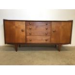 A mid century teak sideboard by John Herbert for A Younger. Four central drawers flanked by two