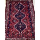A red ground Persian rug featuring birds and flora with a trio of central medallions on blue