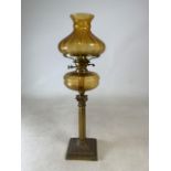 Victorian amber glass oil lamp with brass column base Height:72 cm