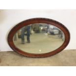 A wooden framed, oval, bevel edge mirror. Depth of frame 7.5cm W:95cm x D:3cm x H:68cm