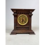A late 19th early 20th Century stained oak cased American shelf clock with decorative dial, bezel