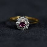 An 18ct gold ruby and diamond flower ring, centrally set with round free cut ruby with a surround of