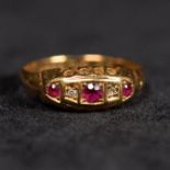 An 18ct gold three stone ruby ring with single cut diamond accents. 2.6g. Size Q.