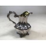 An early Victorian sterling silver jug of heavy gauge with scrolling handle and chased decoration