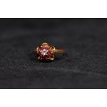 A 9ct gold ruby and diamond ring. Central illusion set diamond with a surround of six round free cut