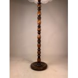 A wooden turned floor lamp with a fringed shade. H:175cm (with shade)