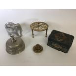 A collection of metal items to include a brass trivet, brass weights, a bell and a Smiths crisps