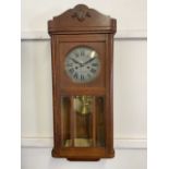 An oak cased mid century wall clock with bevelled glass windows. W:30cm x D:15cm x H:77cm