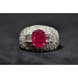 An 18ct white goild ruby and diamond ladies dress ring. Central oval free cut ruby in four claw