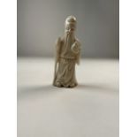 A carved Oriental immortal on Woden stand. H:9cm