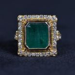 An 18ct gold emerald and diamond ring. Rectangular plaque set with central 12 mm x 10 mm step cut