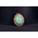 A 14k gold and turquoise set pendant. central oval cabochon cut turquoise with rope twist gold