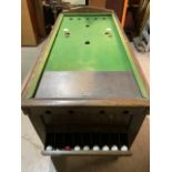 A bar billiards table with oak frame and legs with score rack and balls, wooden table top cover