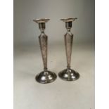 A pair of unmarked white metal candlesticks on circular bases. H:22cm