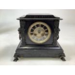 A French black slate mantle clock with bronzed metal feet and lion loop carrying handles. Gilt brass