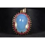 An 18ct gold moonstone and ruby set pendant. Large central cabochon cut moonstone :37mm x:28mm x