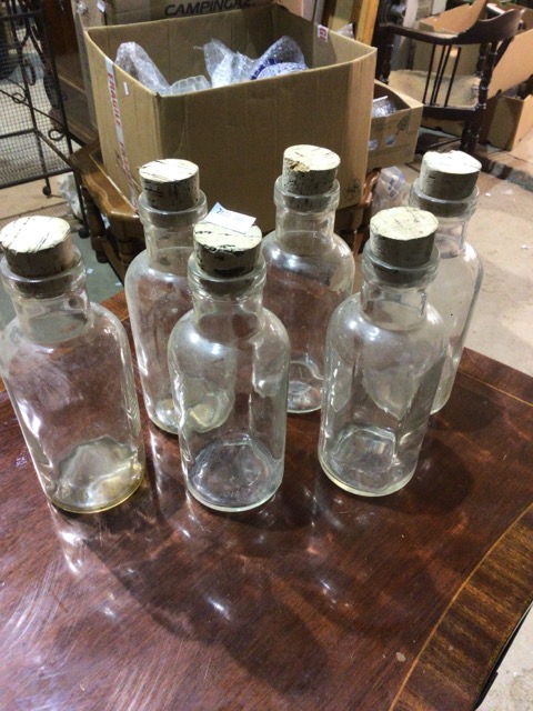 Six glass bottles with cork stoppers.