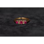 An 18ct gold ruby and diamond ring. Set with three round free cut rubies in colette setting with