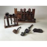 Two wooden pipe racks with a collection of pipes and pipe accessories. Largest pipe rack styled as a