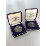 Two sterling silver commemorative medals.