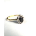An 18ct gold sapphire and diamond dress ring. Central free cut oval sapphire with a surround of