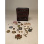 A miniature painted chest of drawers with costume jewellery including two brooches by Sphinx Chest